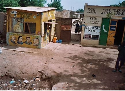 Two makeshift houses decorated in bright colors.  They are surrounded by dirt with debris in the forefront