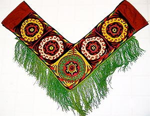 Red V shaped embroidered cloth with green fringe.  Saye Gosha or Segusha is a decoration for bedding