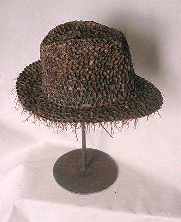 Sculpture of a hat that looks like a fedora made out of seed pods and bee's wax 