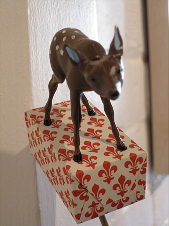 Deer standing on a small paper box that is elevated 