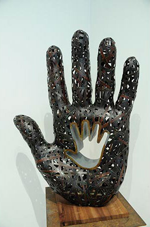 Sculpture of black hand.  There is a white hand pressed into the palm of the black hand 