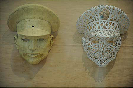 Two maquette sculptures of a man's head wearing a military hat 