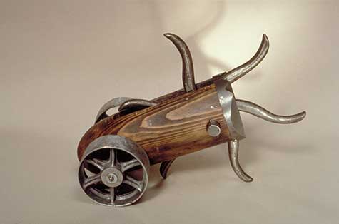 Metal and wood sculpture with wheels and producing sharp metal objects by Bella Feldman