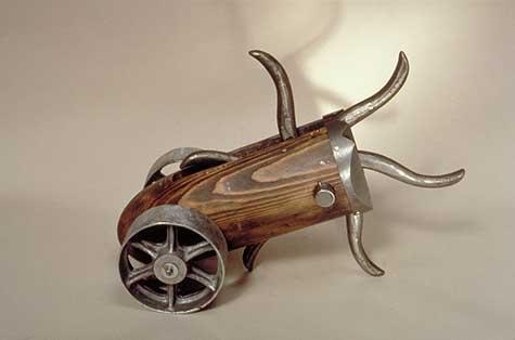 Metal and wood sculpture with wheels and prodding sharp metal objects by Bella Feldman