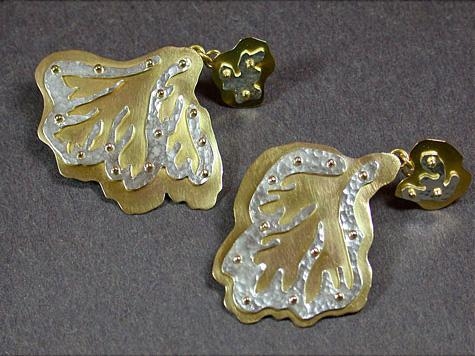 Gold and silver earrings that resemble leaves